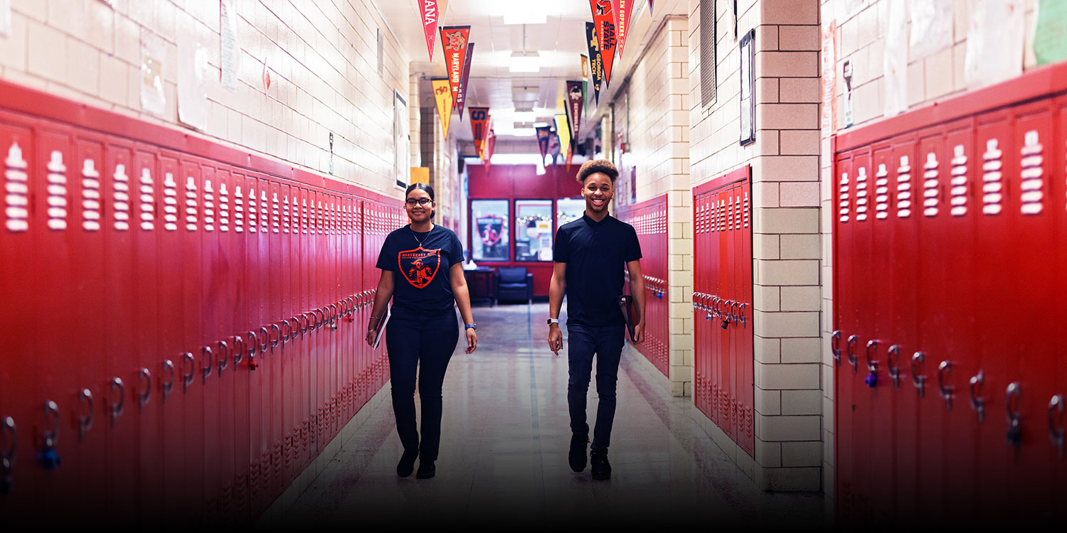 Smiling students walking down NEO hallway.